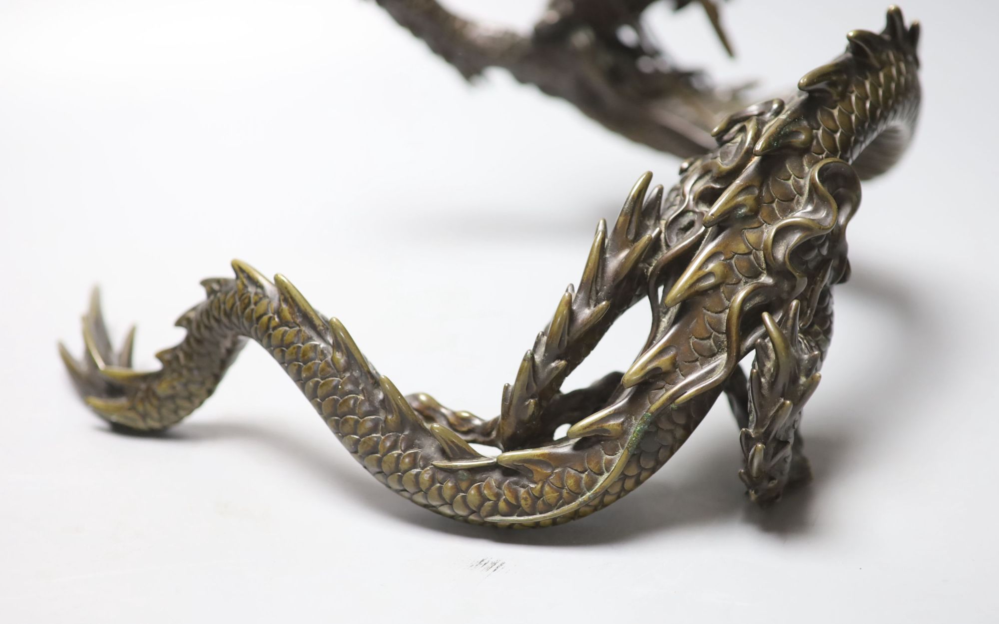 A large Japanese bronze model of a dragon clasping a glass jewel, 29.5cm across